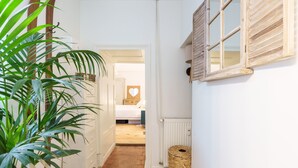 A narrow hallway with a potted plant, a wicker basket, and a bed visible in the background. - L’Escapade Bourguignonne - Centre-ville de Dijon (Dijon)