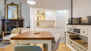 A modern kitchen with white cabinets, a wooden table, and a built-in oven. - L’Escapade Bourguignonne - Centre-ville de Dijon (Dijon)