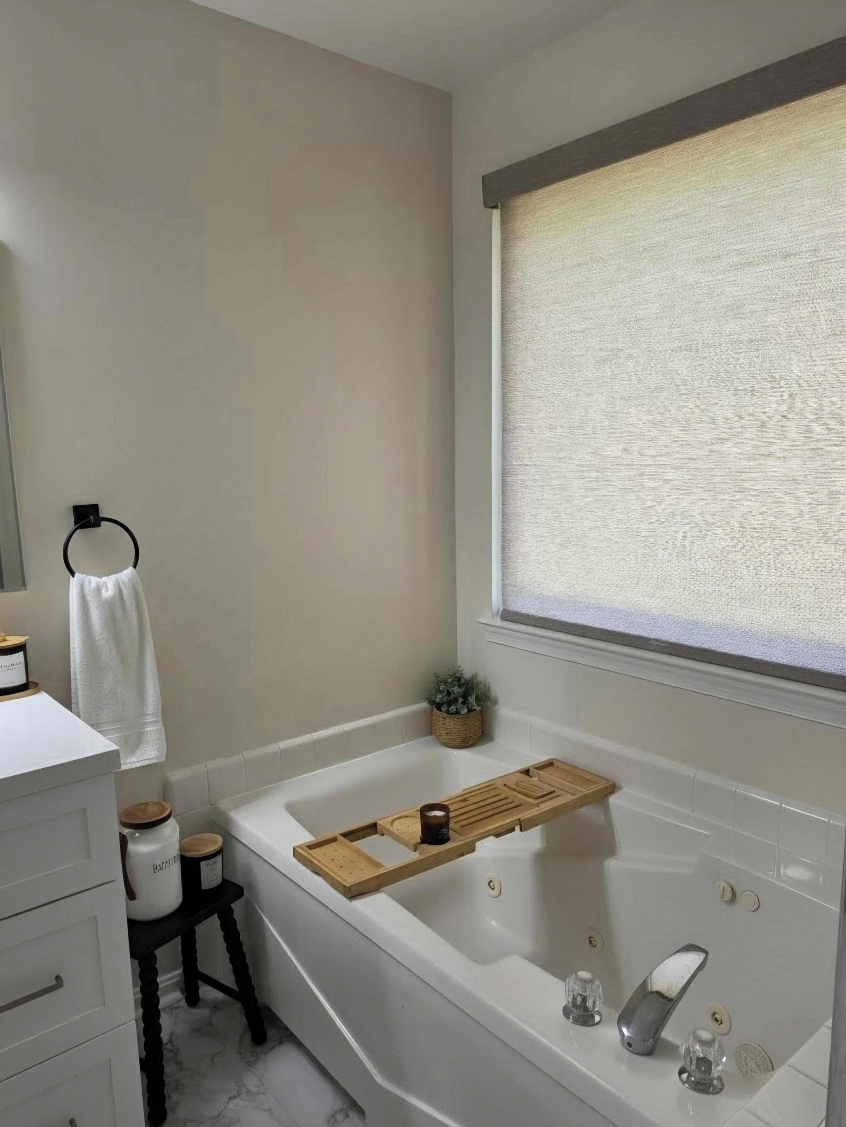 Une salle de bain moderne avec une baignoire, un plateau en bois, une petite plante et une fenêtre donnant sur un beau paysage.