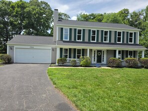 A two-story house with a garage, a front porch, and a well-maintained lawn. - Spacious Colonial-style single-family home (Waldorf)