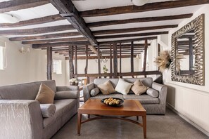 A living room with a wooden ceiling, two sofas, a coffee table, and a decorative mirror.