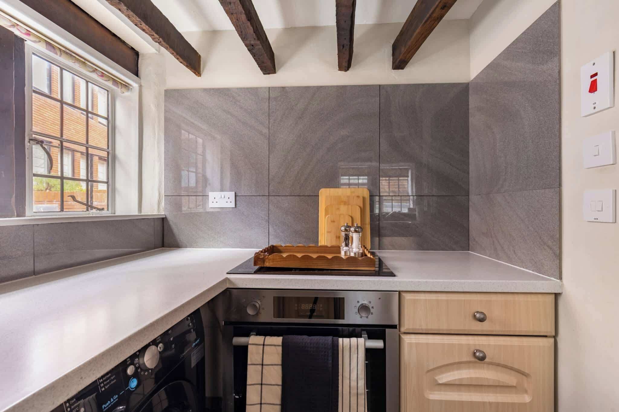 A kitchen with a dishwasher, oven, and wooden cutting board on the counter.