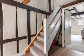 A staircase with a wooden handrail and carpeted steps leading to a room with a white door.