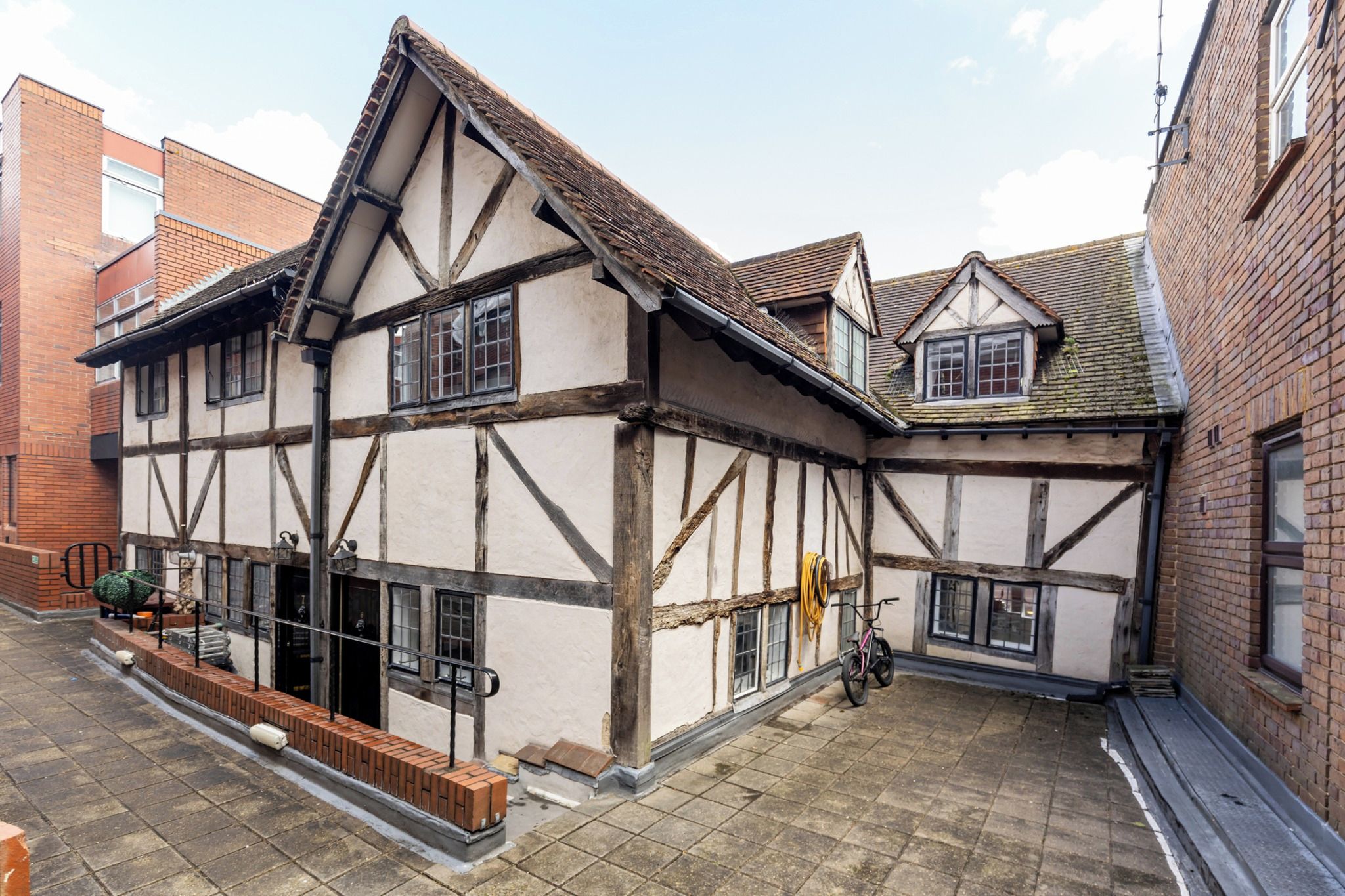 A traditional half-timbered building with a courtyard, a bicycle, and a hose coiled on the wall.