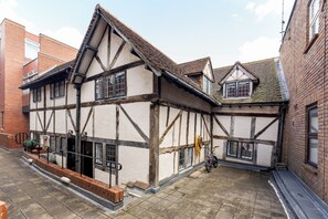 A traditional half-timbered building with a courtyard, a bicycle, and a hose coiled on the wall.