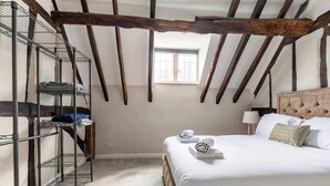 A bedroom with a bed, a window, a lamp, and a metal shelf unit. - Grade II Listed Tudor Charm by Windsor Castle (Windsor)
