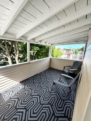 A covered outdoor seating area with a patterned floor, white walls, and a view of buildings and trees. - 5AC Driveway
4BR
Tufts ~ Downtown Boston (Somerville)