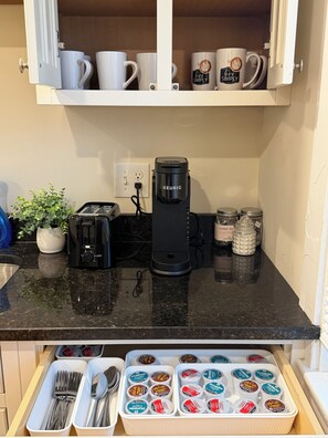 Eine Küche mit einer Keurig-Kaffeemaschine, einem Toaster und einer Schublade voller McCafé-Kaffeekapseln.