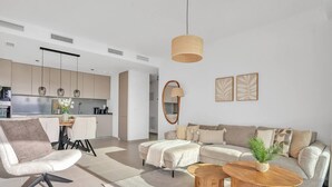 Een moderne woonkamer met een bank, salontafel en een eethoek met stoelen en een tafel.