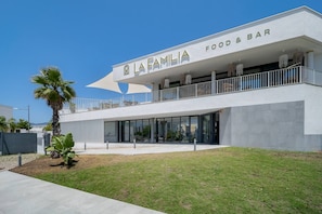 A modern building with a sign reading 'LA FAMILIA FOOD & BAR' on the upper level. - Oceana Gardens Apartment (Cancelada)