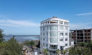 Un hotel blanco con esquina curva, ventanas amplias y vistas al mar.