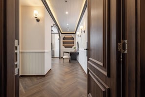 A hallway with wooden flooring, wall-mounted lighting, and a door on the right. - Can Gio Park Hotel (Can Gio)