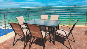 Un tavolo e delle sedie su una terrazza con vista sull'oceano e su una scogliera.