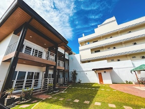 Un edificio moderno con techo plano, varios balcones y un césped bien cuidado.