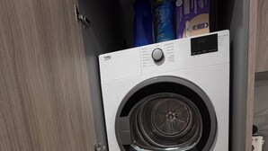 Una lavatrice compatta, a due ante, con pannello di controllo sulla porta superiore.