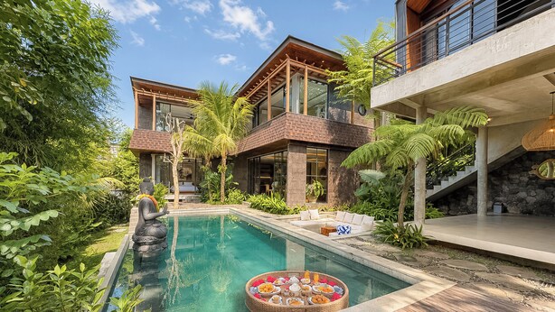 Ein modernes Resort mit Pool, üppiger Bepflanzung und einer Buddha-Statue.