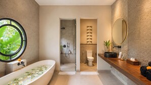 Ein modernes Badezimmer mit einer freistehenden Badewanne, einer Dusche, einer Toilette und einem Waschtisch mit Spiegel.