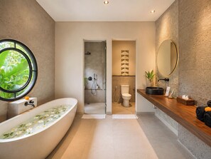 Un baño moderno con una bañera independiente, ducha, inodoro y tocador con espejo.