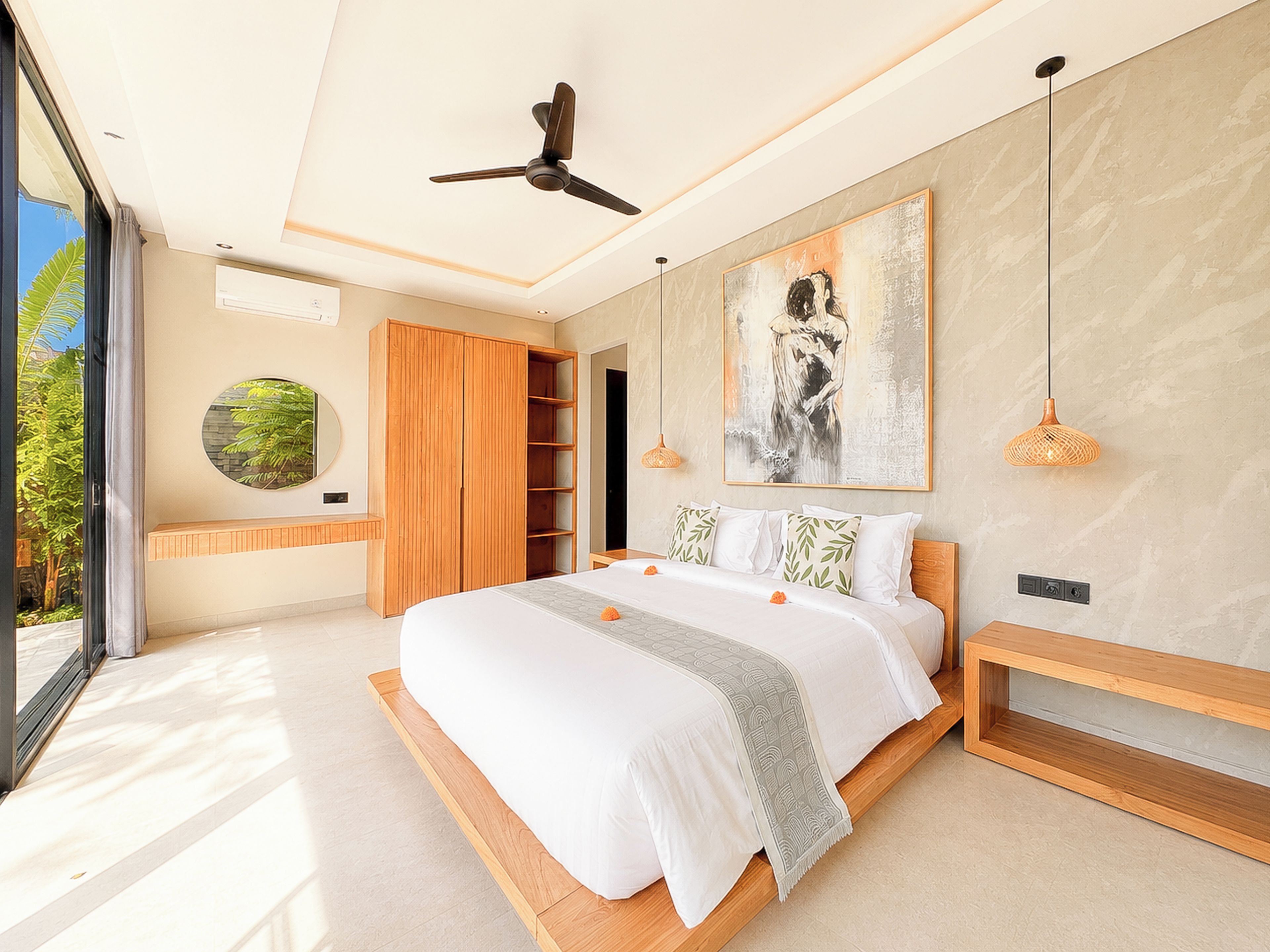 Un dormitorio moderno con una cama grande, un ventilador de techo, una obra de arte en la pared y vistas a zonas verdes al exterior.