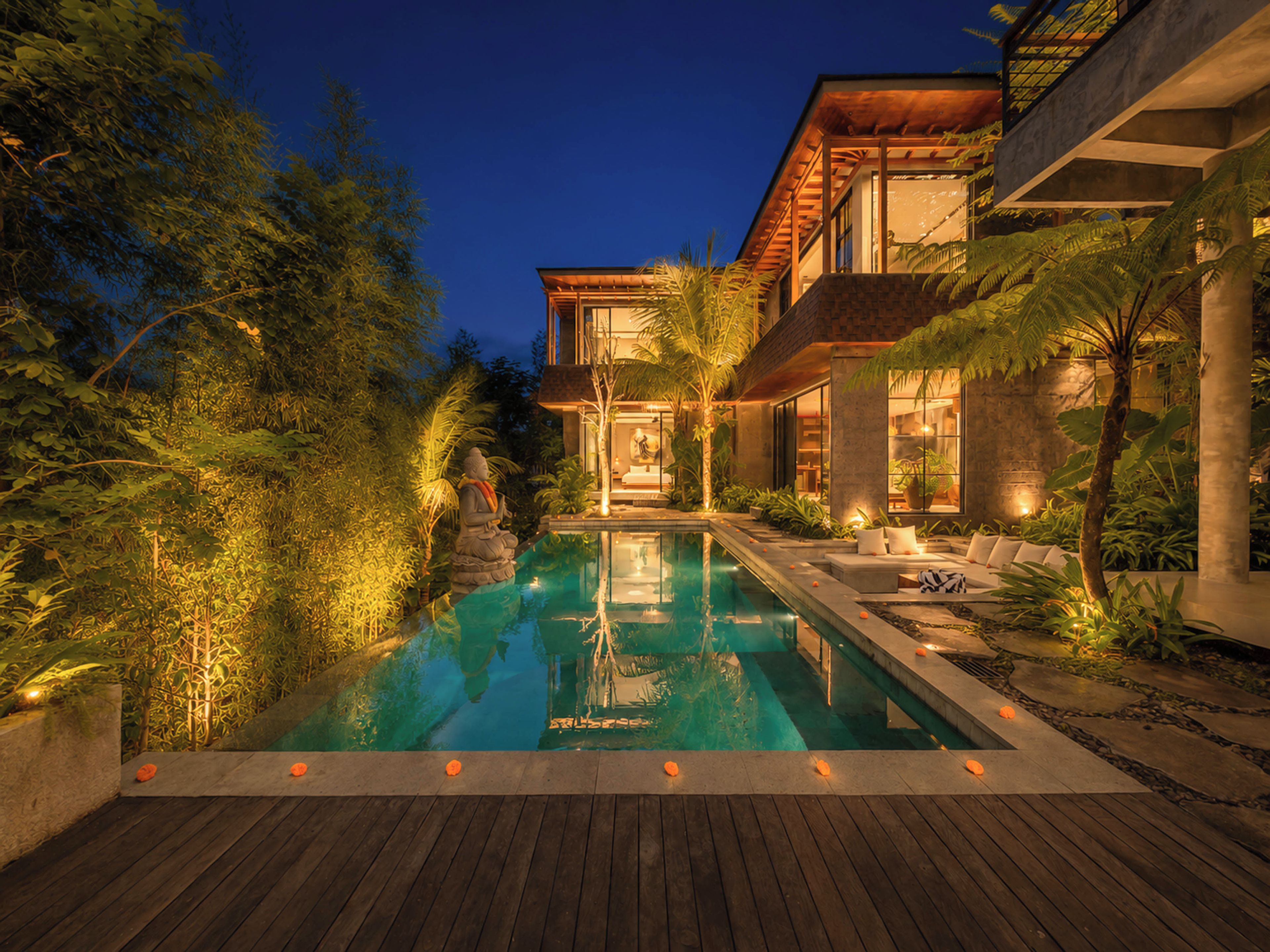 Una casa moderna con piscina, rodeada de exuberante follaje y una terraza de madera.