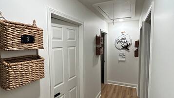 A hallway with white walls, a wooden floor, and baskets on the wall.