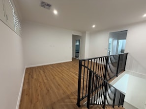 A spacious room with wooden flooring, a black railing, and a door leading to another room. - Modern Brand new Spacious Home 4BDR in Maylands (Maylands)