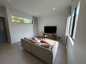Un salon moderne avec un canapé, un téléviseur et une table à manger.