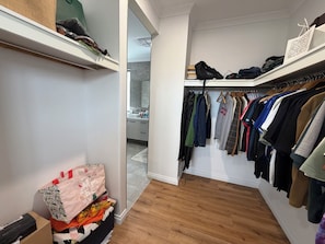 A walk-in closet with wooden flooring, a variety of hanging clothes, and a shoe rack with multiple pairs of shoes. - Modern Brand new Spacious Home 4BDR in Maylands (Maylands)
