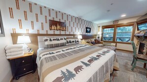 Una camera d'albergo con un letto, un comodino, una lampada, un divano, un camino e una finestra con vista.