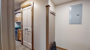 Un corridoio con una porta doppia, un quadro elettrico a parete e una zona cucina sullo sfondo.