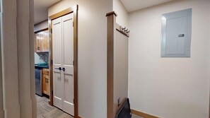 A hallway with a double door, a wall-mounted electrical panel, and a kitchen area in the background. - Cozy 1-bedroom Rimfire Studio - 257 Village View (Slaty Fork)