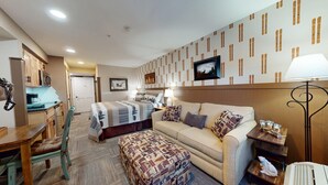Camera d'albergo con un letto, un divano, un tavolino, una lampada e una parete decorata con un motivo a sci.