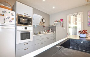 A modern kitchen with a refrigerator, microwave, oven, and a coffee machine. - Cozy home in Bagnoles (Bagnoles)