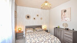 Una camera da letto con una coperta a motivi, una testiera in legno, lampade sui comodini, una sveglia a parete e decorazioni murali.