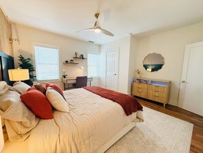 Ein Schlafzimmer mit Bett, Schreibtisch, Stuhl und Deckenventilator.