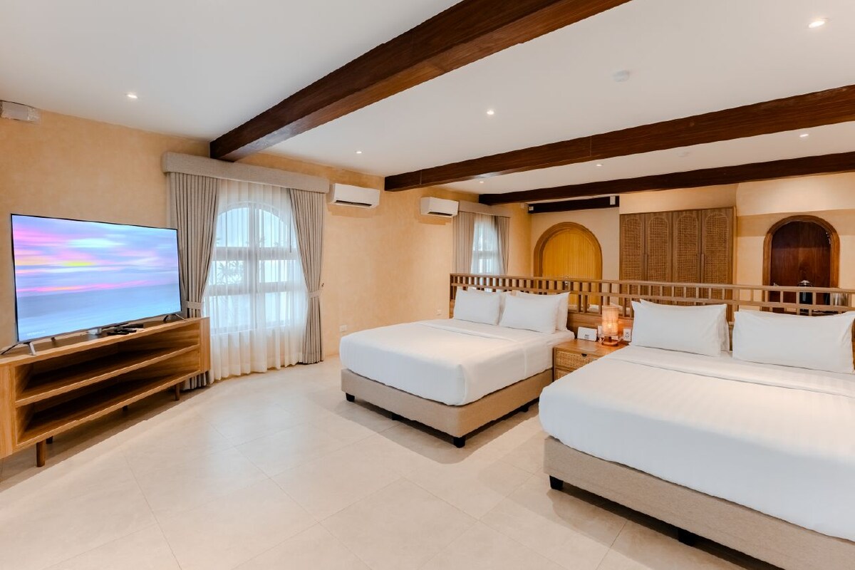 A hotel room with a large bed, a smaller bed, a TV, and a wooden entertainment unit.