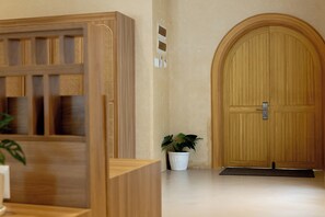 A wooden reception desk, a potted plant, and a large wooden door.