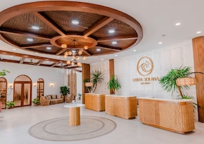 Zona de recepción con techo de madera, una mesa de recepción y un letrero en la pared para Costa Solana Resort.