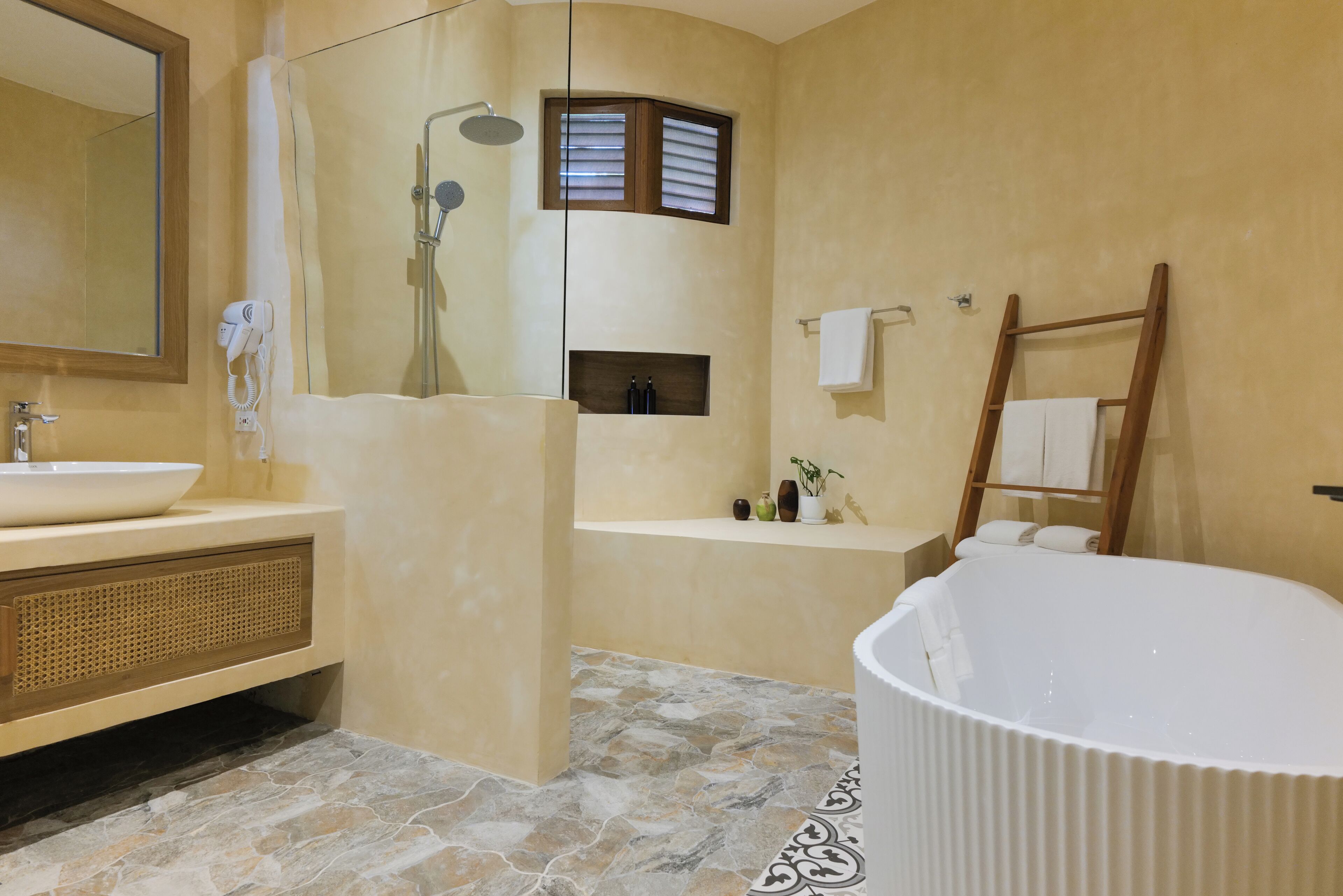 A bathroom with a bathtub, a shower, a vanity with a sink, and a mirror.