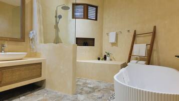 A bathroom with a bathtub, a shower, a vanity with a sink, and a mirror.