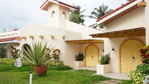 A building with a red-tiled roof, a central entrance with a wooden door, and a small tower-like structure.