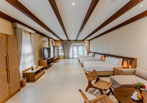 Habitación de hotel con televisión, dos camas, sofá, mesa de comedor y mueble para televisión.