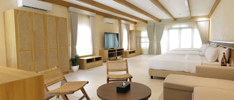 Una habitación de hotel moderna con una cama grande, un sofá, una mesa de comedor, sillas de mimbre y un televisor.
