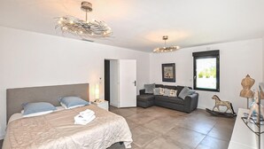 Een moderne slaapkamer met een bed, een sofa, een kroonluchter en een raam.