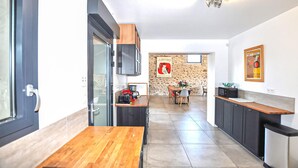 Een moderne keuken met een houten tafel, een stenen muur en een eethoek met stoelen.