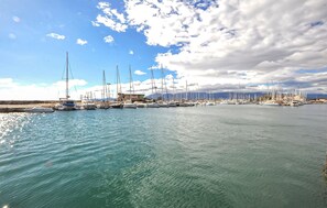 Ein Yachthafen mit zahlreichen Segelbooten, ruhiges Wasser und einem wolkenlosen Himmel.