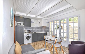 A compact kitchen with a washing machine, a microwave, and a dining area with a table and chairs. - 1 bedroom gorgeous home in Saint Cyprien Plage (Saint Cyprien Plage)