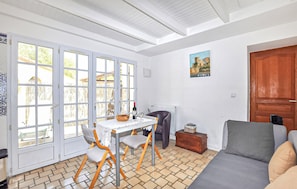 Ein Zimmer mit Esstisch, Stühlen, einer Couch, einer Holztür und einem Fenster mit Blick.