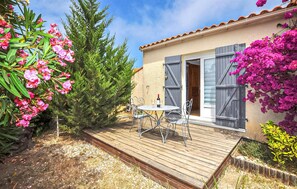 A patio with a table and chairs, a bottle of wine, and a wooden deck. - 1 bedroom gorgeous home in Saint Cyprien Plage (Saint Cyprien Plage)