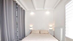 Ein Schlafzimmer mit Bett, Vorhängen, zwei Wandleuchten und einer Heizung.